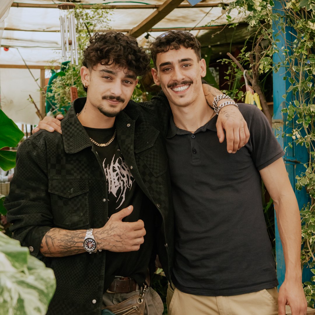 שני חברים מתחבקים וצוחקים בין הצמחים במשתלה